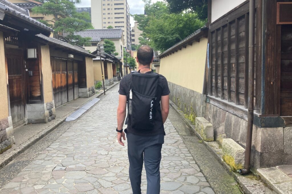 man walking with backpack down street in tokyo