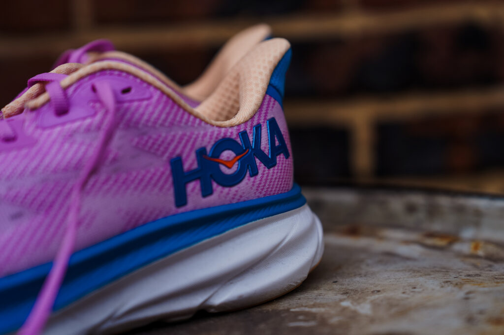 side back of a purple hoka shoe on a sidewalk