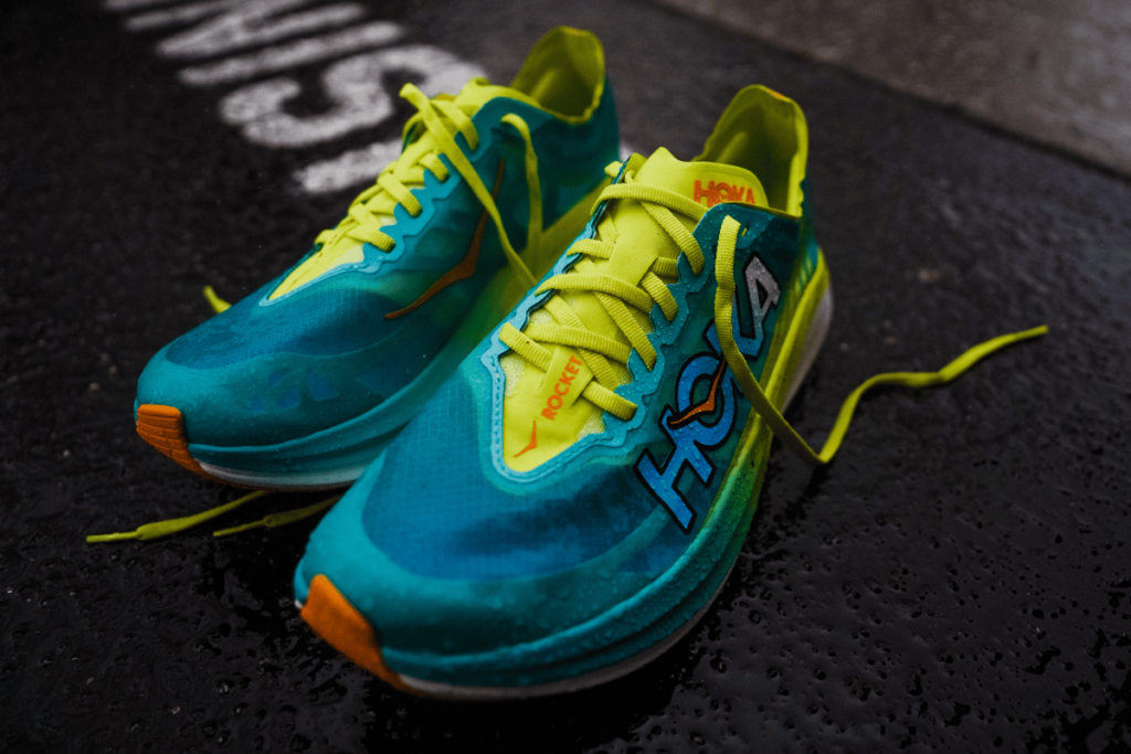 hoka rocket x 2 with neon yellow shoelaces sitting on a sidewalk