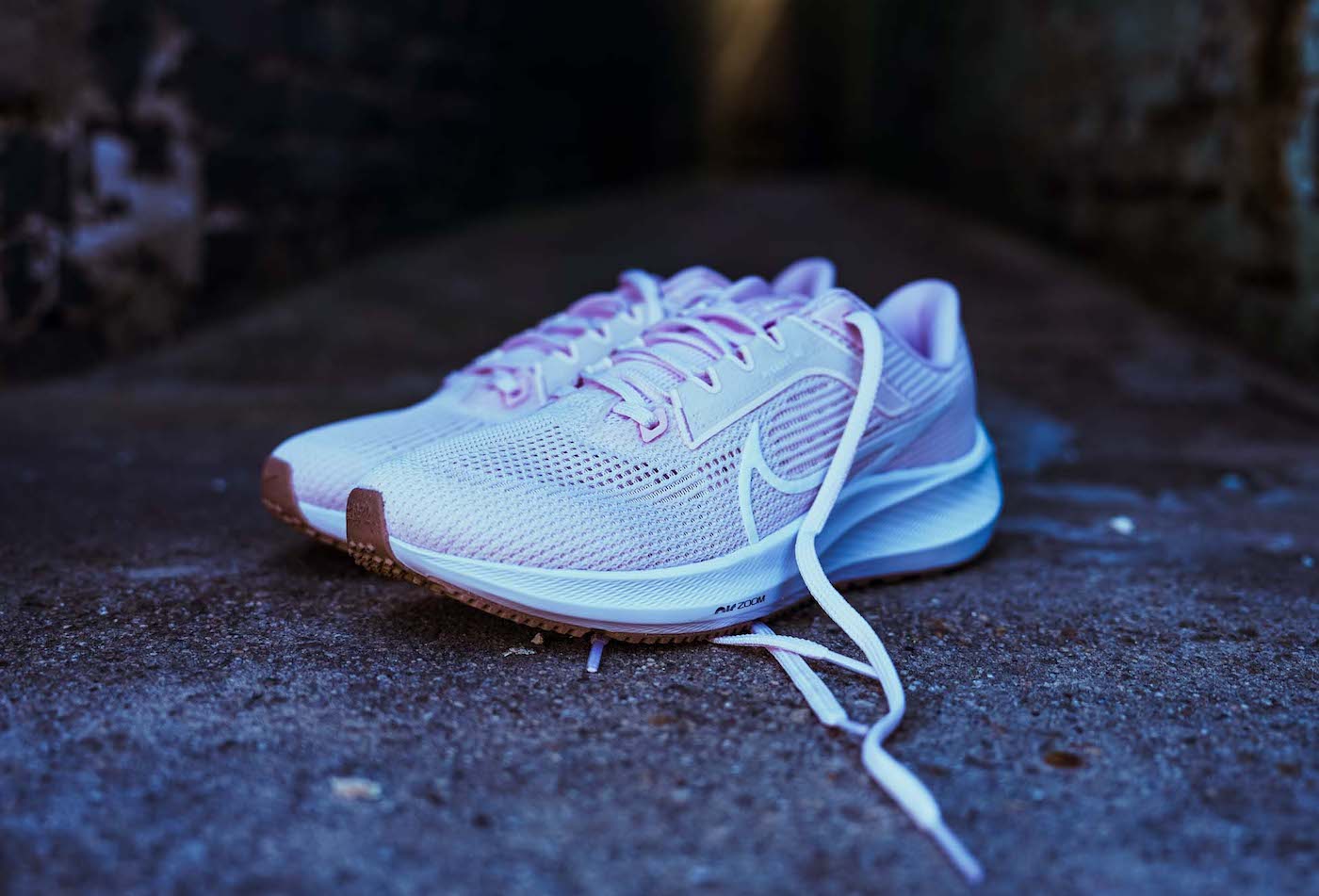pink women's nike shoe on pavement