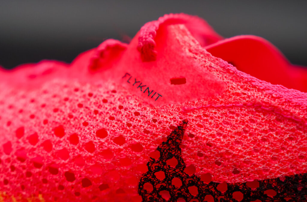 closeup of flyknit upper of pink and orange nike vaporfly next% 3 on a black table