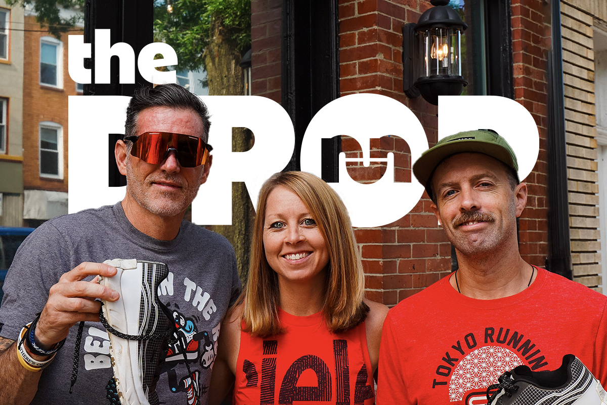 man with red shield sunglasses holding a shoe on the left, woman in red shirt smiling in center, man with mustache on right in red shirt and army green hat