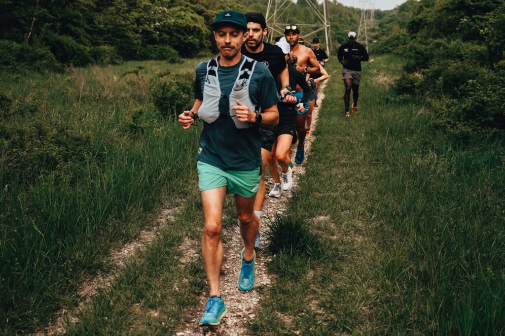 man running on a dirt trail with people behind him
