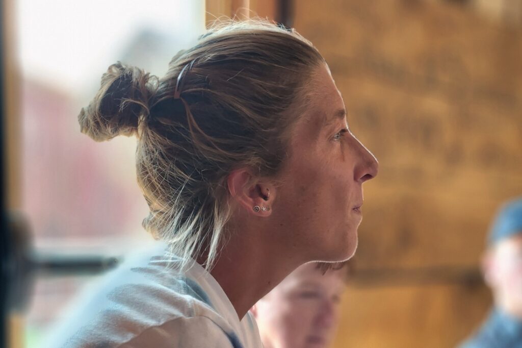 A woman in a white shirt is looking out of a window.