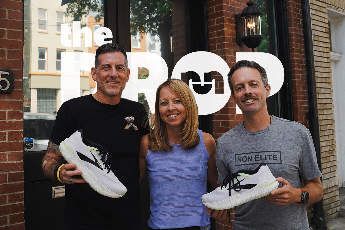 man on left holding white shoe, woman in purple shirt in center, man on right holding white brooks shoe