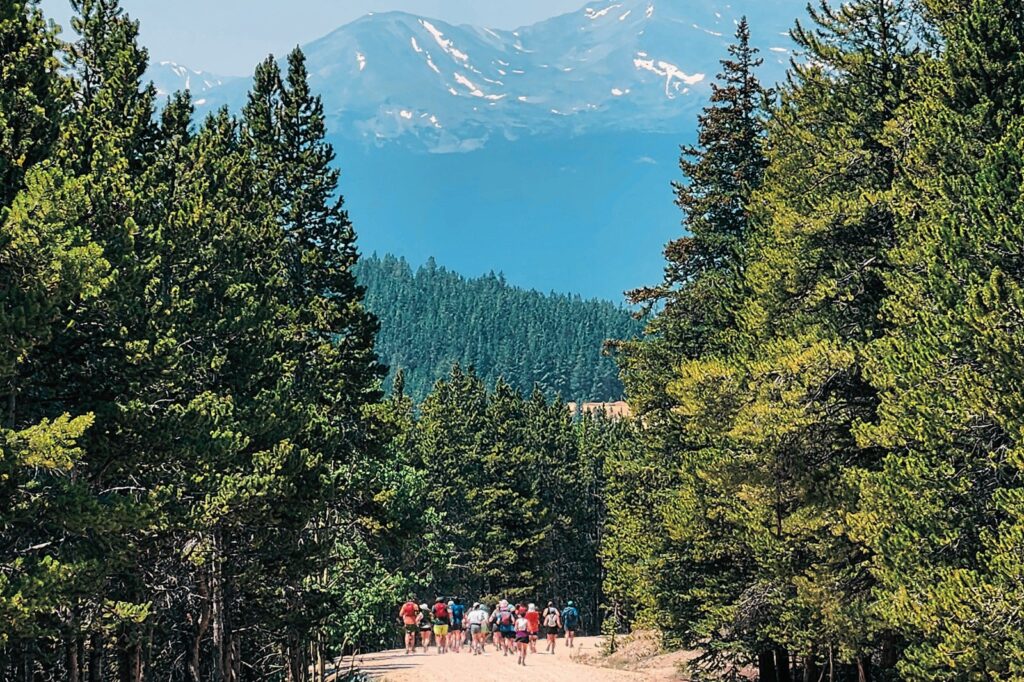 A group of people on a dirt road with mountains in the background.