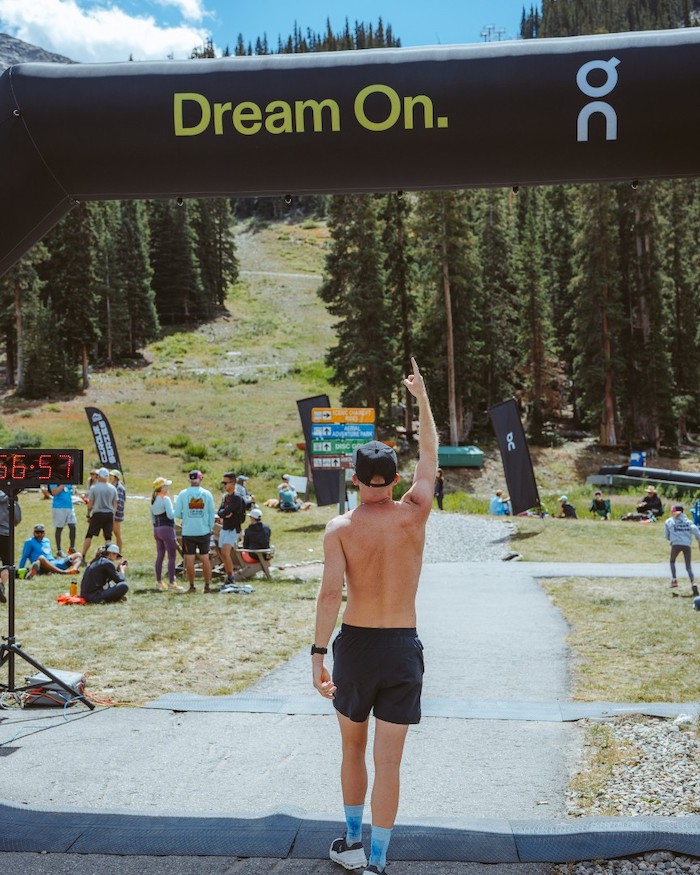 man at finish line of trail race