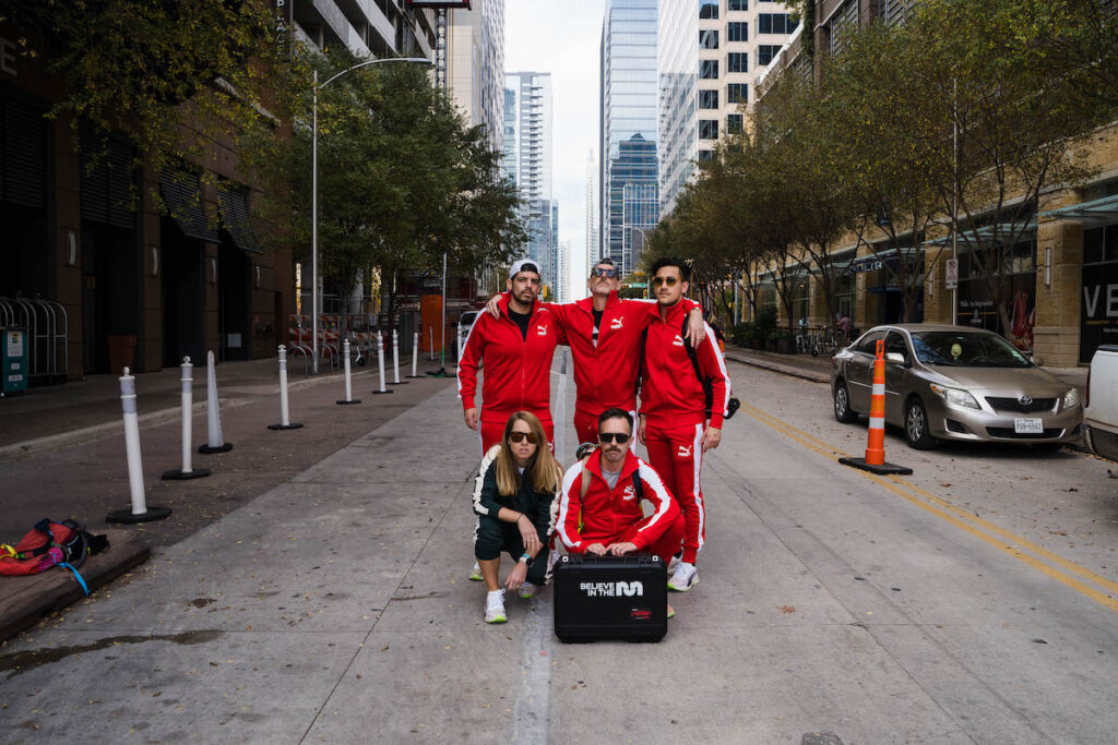 group of five people posing for a photo in an austin texas street wearing red jumpsuits