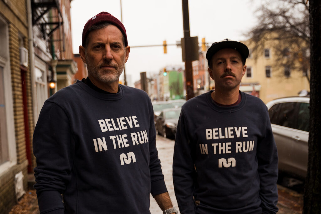 two man looking at a camera in a city