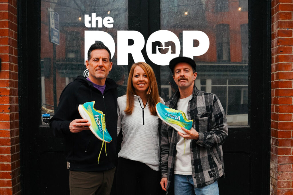 two men and one woman standing on a sidewalk holding a hoka rocket x 2 running shoe