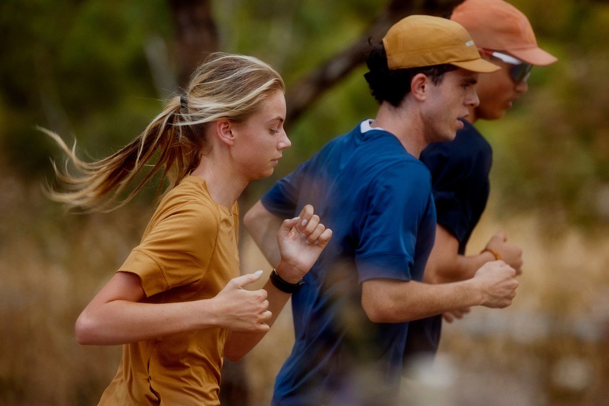 Woman running in orange running tee with a man on the right side running in blue running tee and orange cap