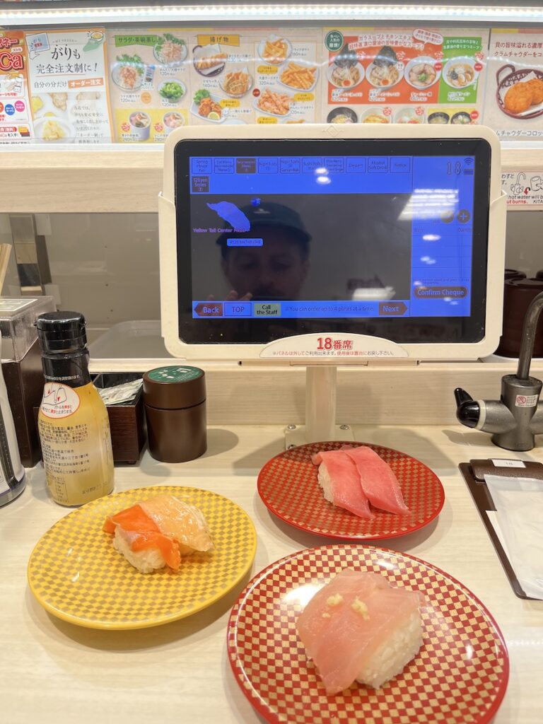 three plates of nigiri sushi at a robot sushi place in japan