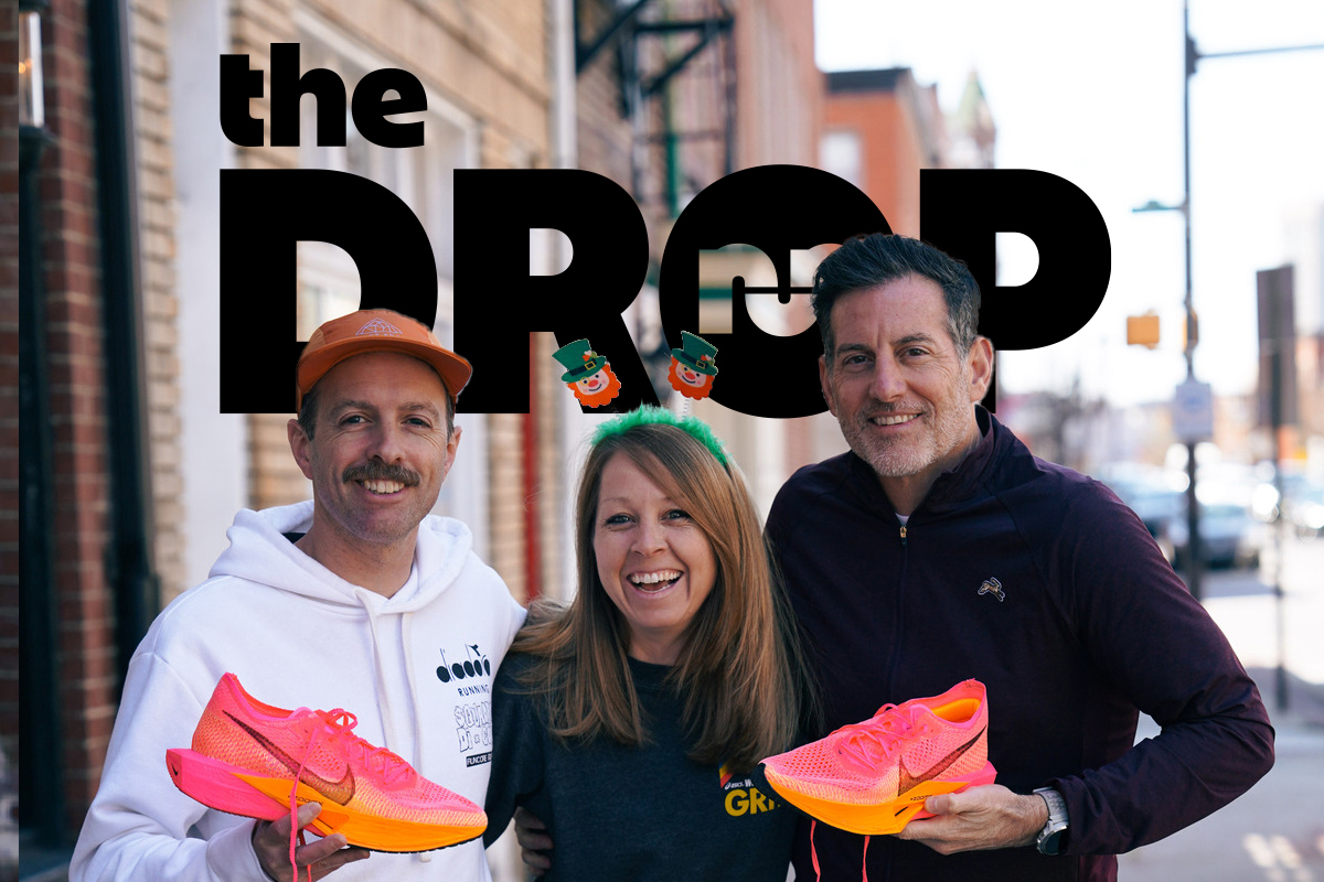 man in white sweatshirt holding a pink shoe on the left, woman in the middle smiling, man on the right holding a pink shoe, outside in the city