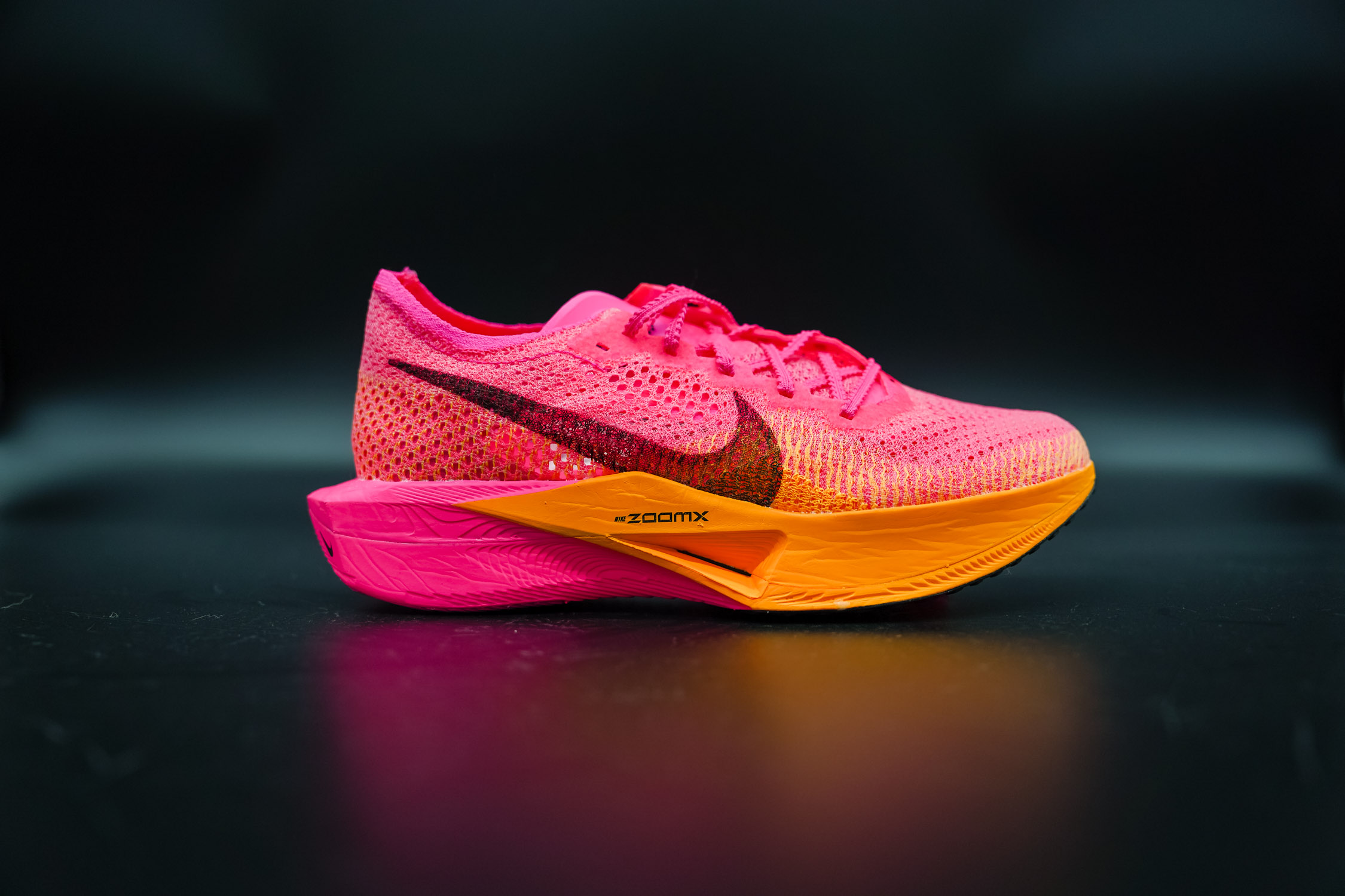 side of a pink and orange nike vaporfly next% 3 on a black table