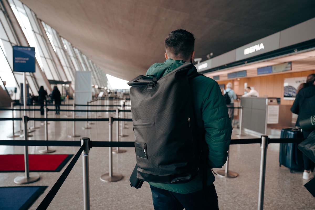 man walking through airport with a black backpack