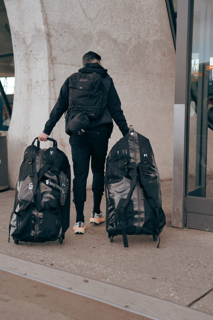 man pulling two large black ortlieb duffel bags into an airport