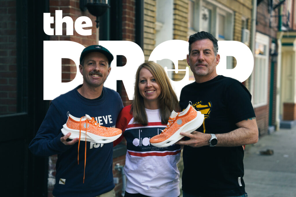 man on left and man on right holding an orange shoe, with a smiling woman in the middle