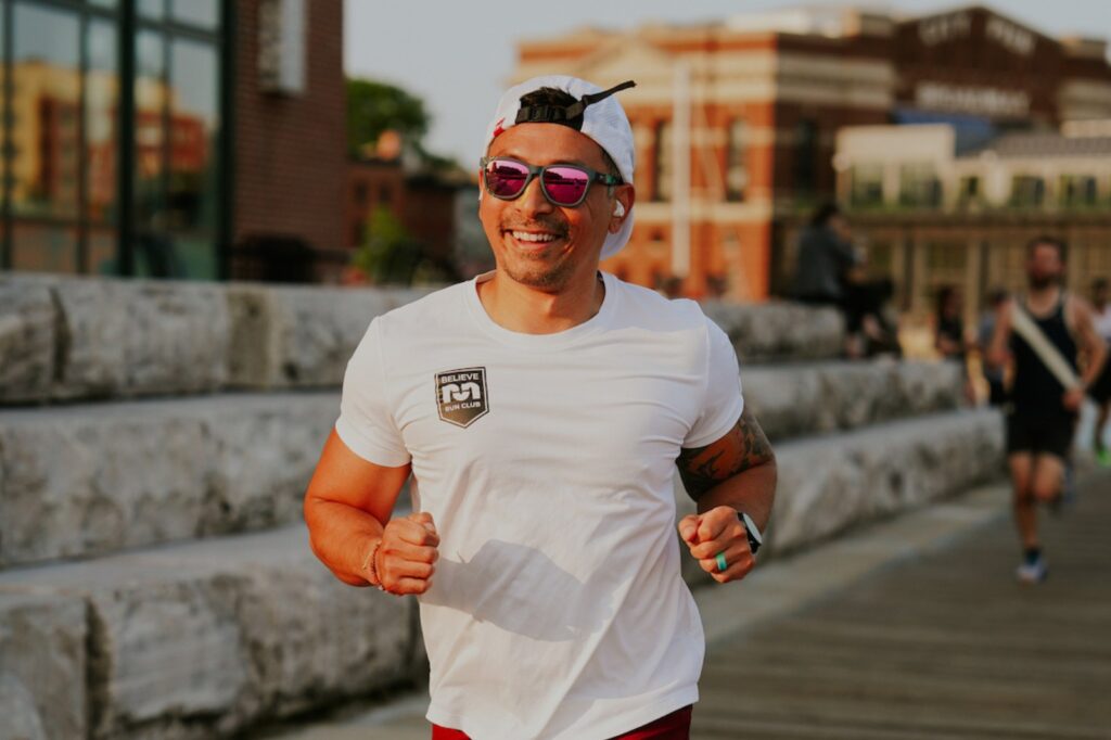 man running in white tshirt and sunglasses with white hat on backwards
