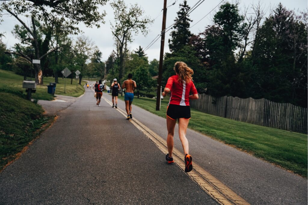 runners running down a long country road