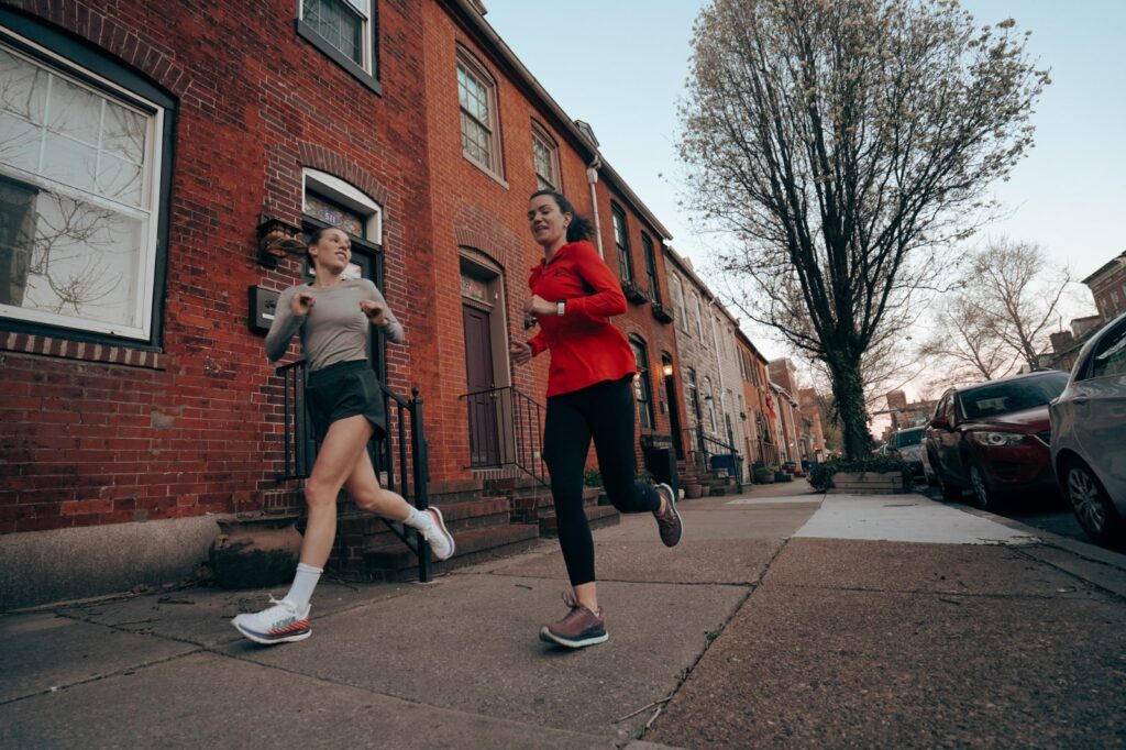 two women running on a city sidewalk