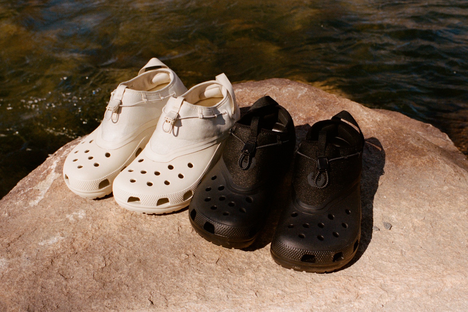 beige and black satisfy x crocs classic clogs sitting on a rock