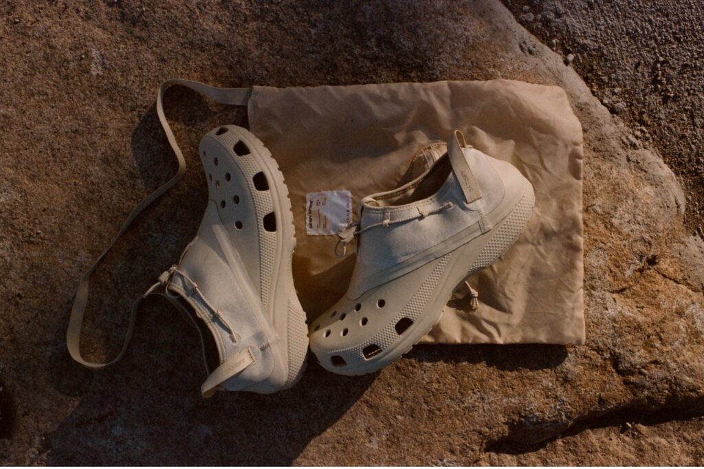 satisfy x crocs classic clog sitting on a carrying bag on a rock