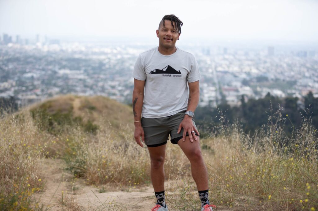 man standing in army green shorts and path projects tee above Los angeles