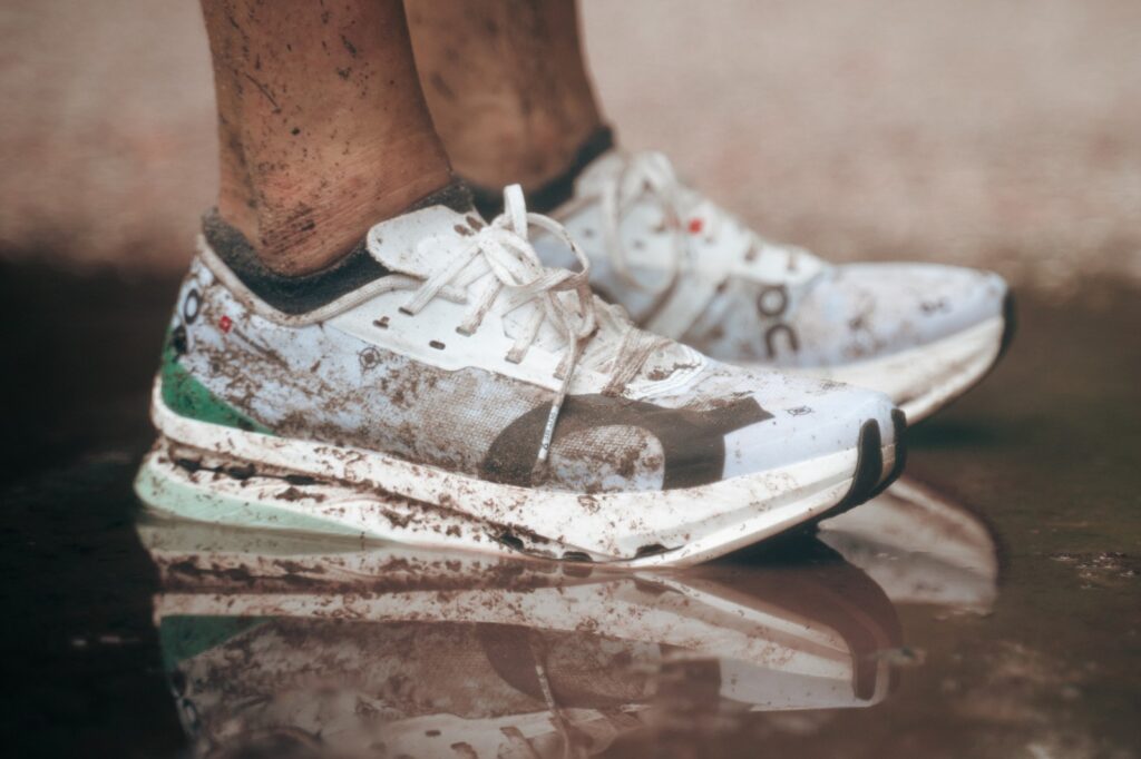 white On racing shoe covered in dirt and mud