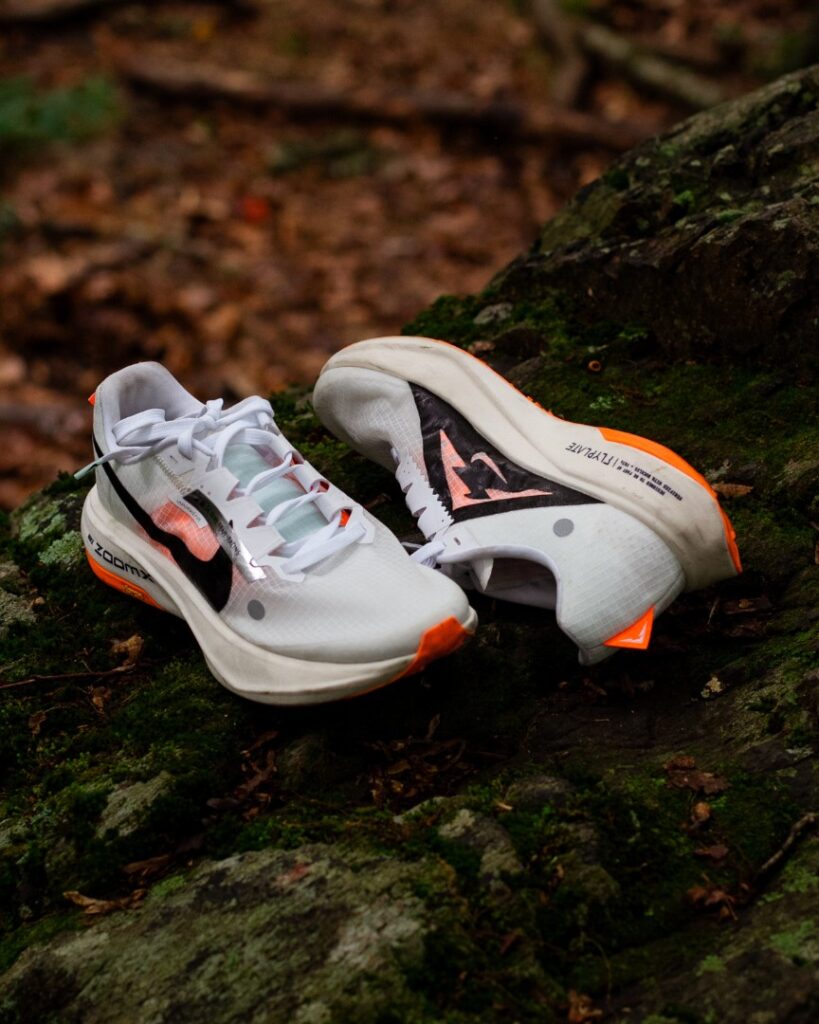 A pair of Nike Ultrafly running shoes on a moss-covered rock in the woods.